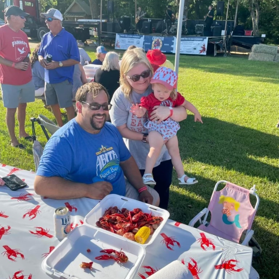 dad, mom, and baby at crawfish boil fundraiser