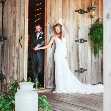 wedding couple holding hands around doorway of barn