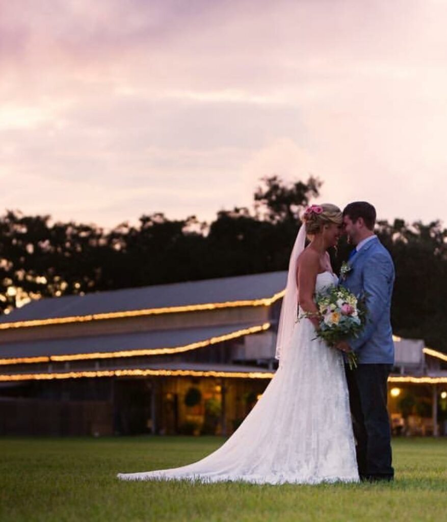 bride and groom holding hands with barn in background at sunset